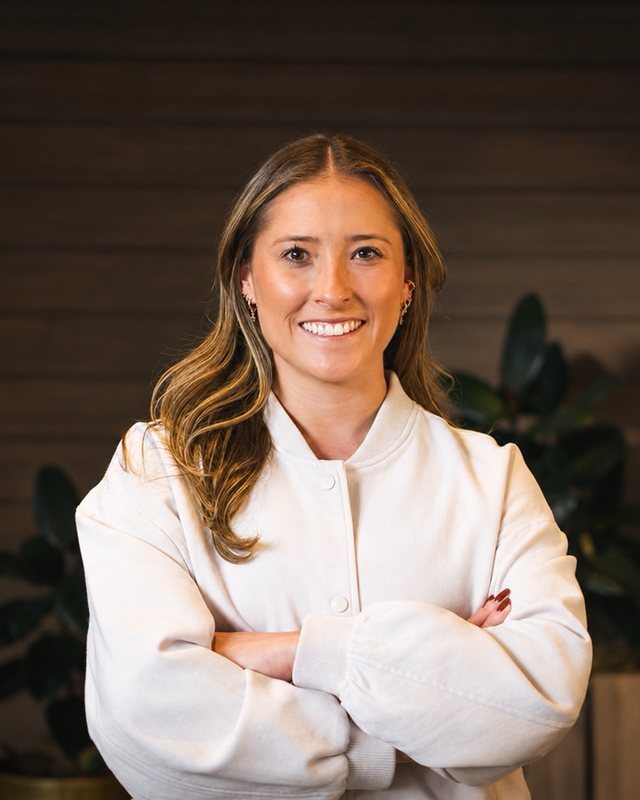A team member smiling with arms crossed